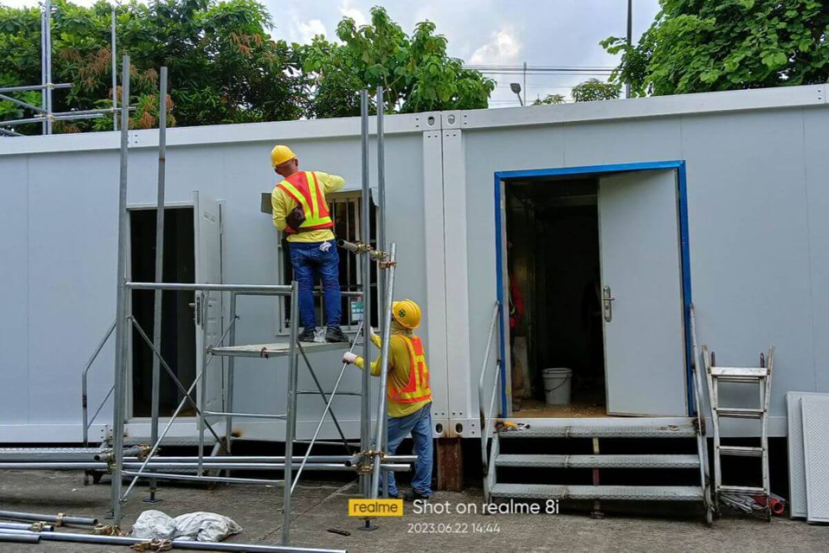 workers installing expandable prefab building