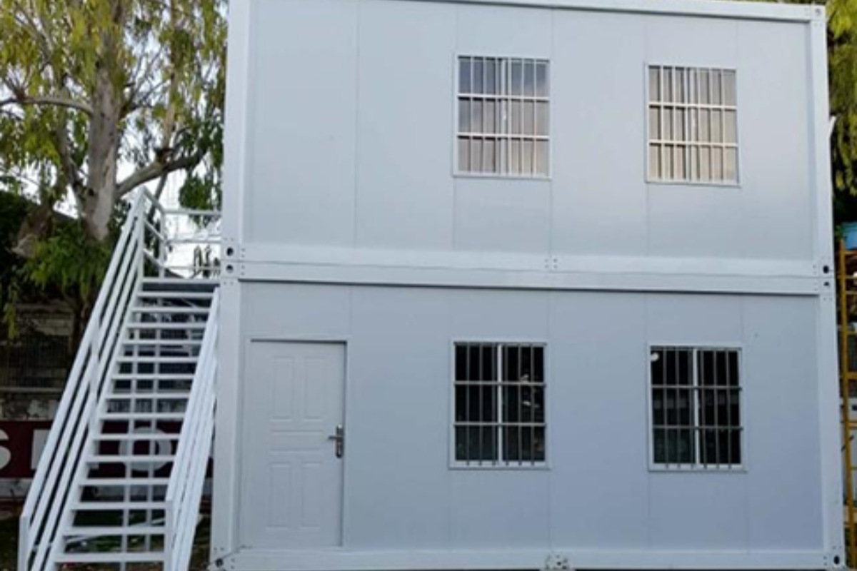 Two-story temporary site office with exterior stairs and barred windows