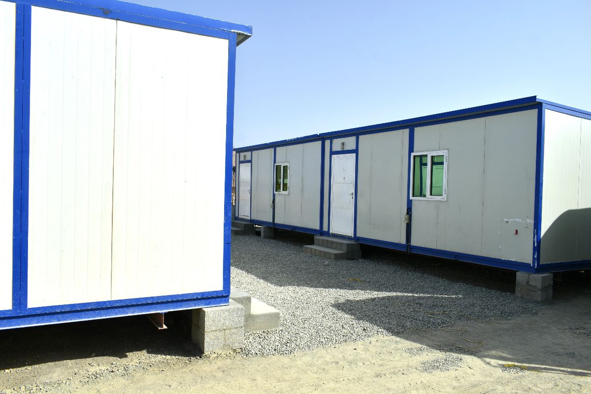 White and blue mobile office containers installed on gravel foundations at a worksite