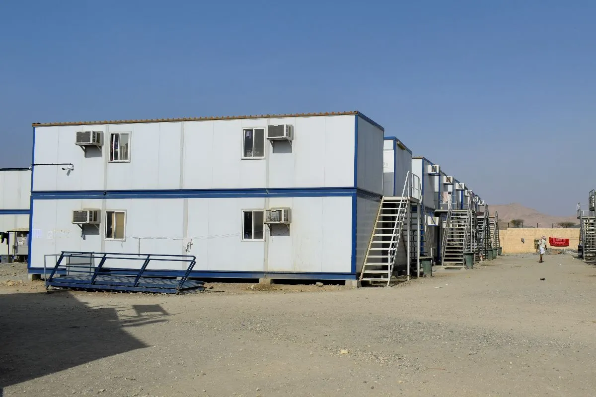 Row of white prefab container units with air-conditioning systems installed at a construction site