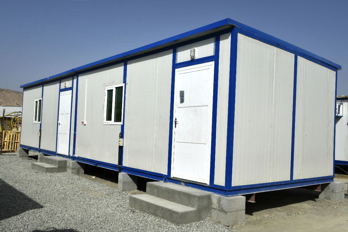 Blue and white modular office building with multiple doors, windows, and concrete step entrances