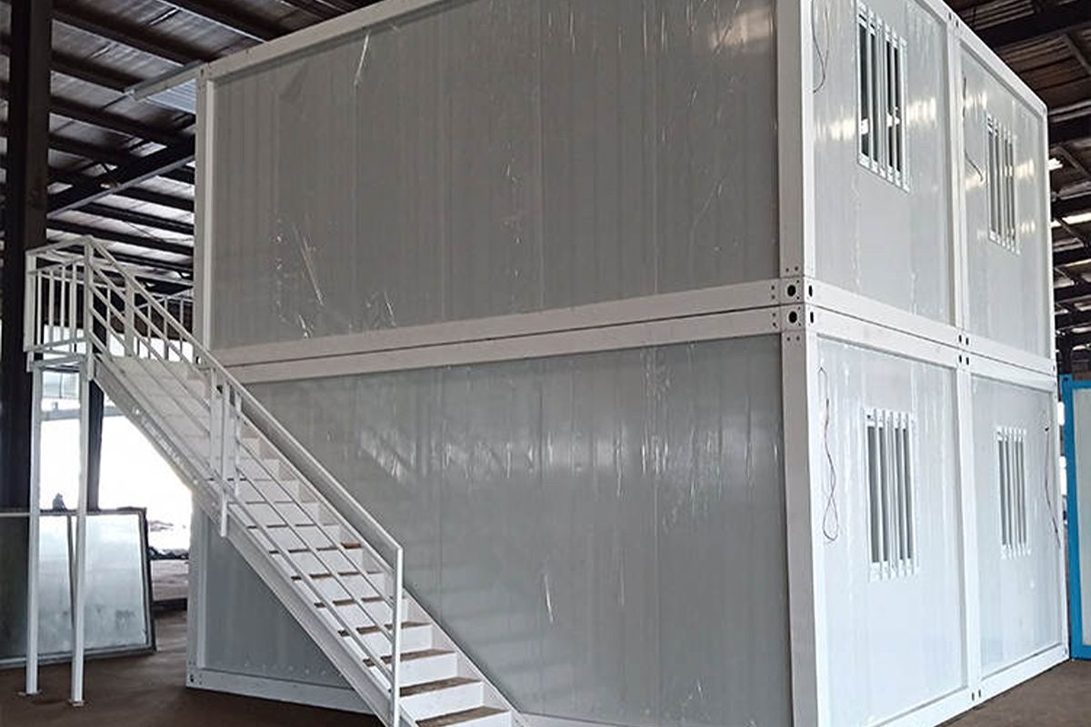 Two-story prefab container building with an exterior staircase and multiple windows