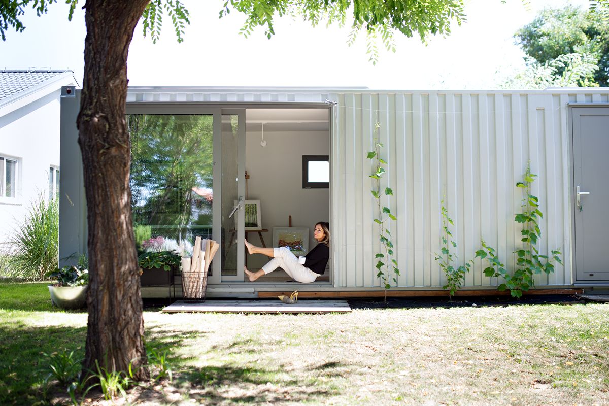 Modular container workspace with an open entrance, large windows, and a compact interior office setup