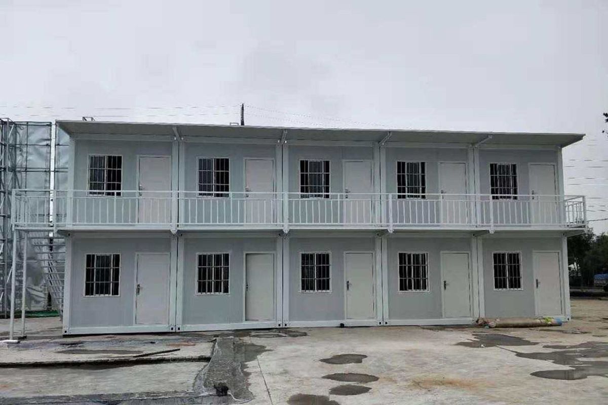 Two-story prefab container building with multiple doors, windows, and an exterior walkway for educational use