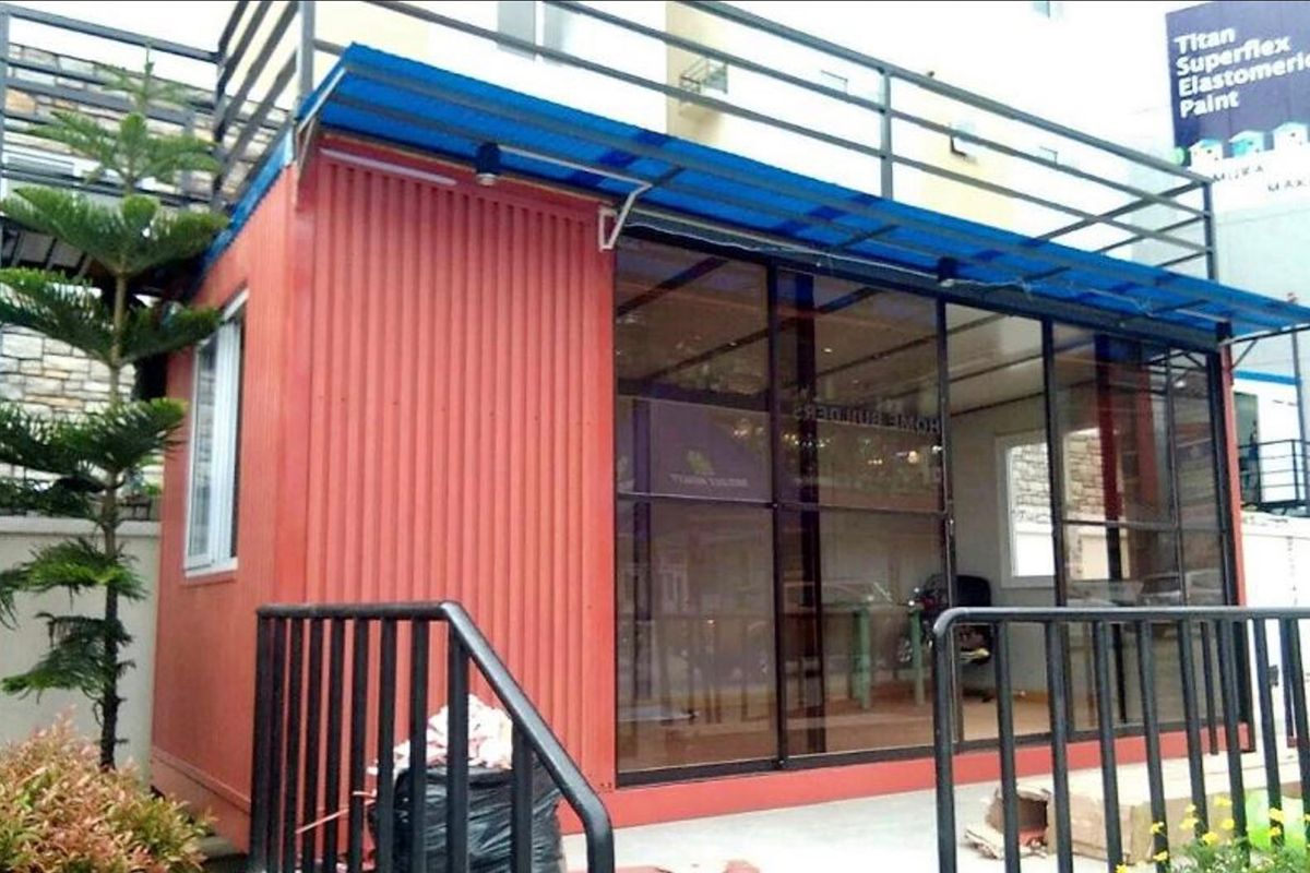 Customized prefab container building with glass storefront windows, metal framing, and an exterior awning