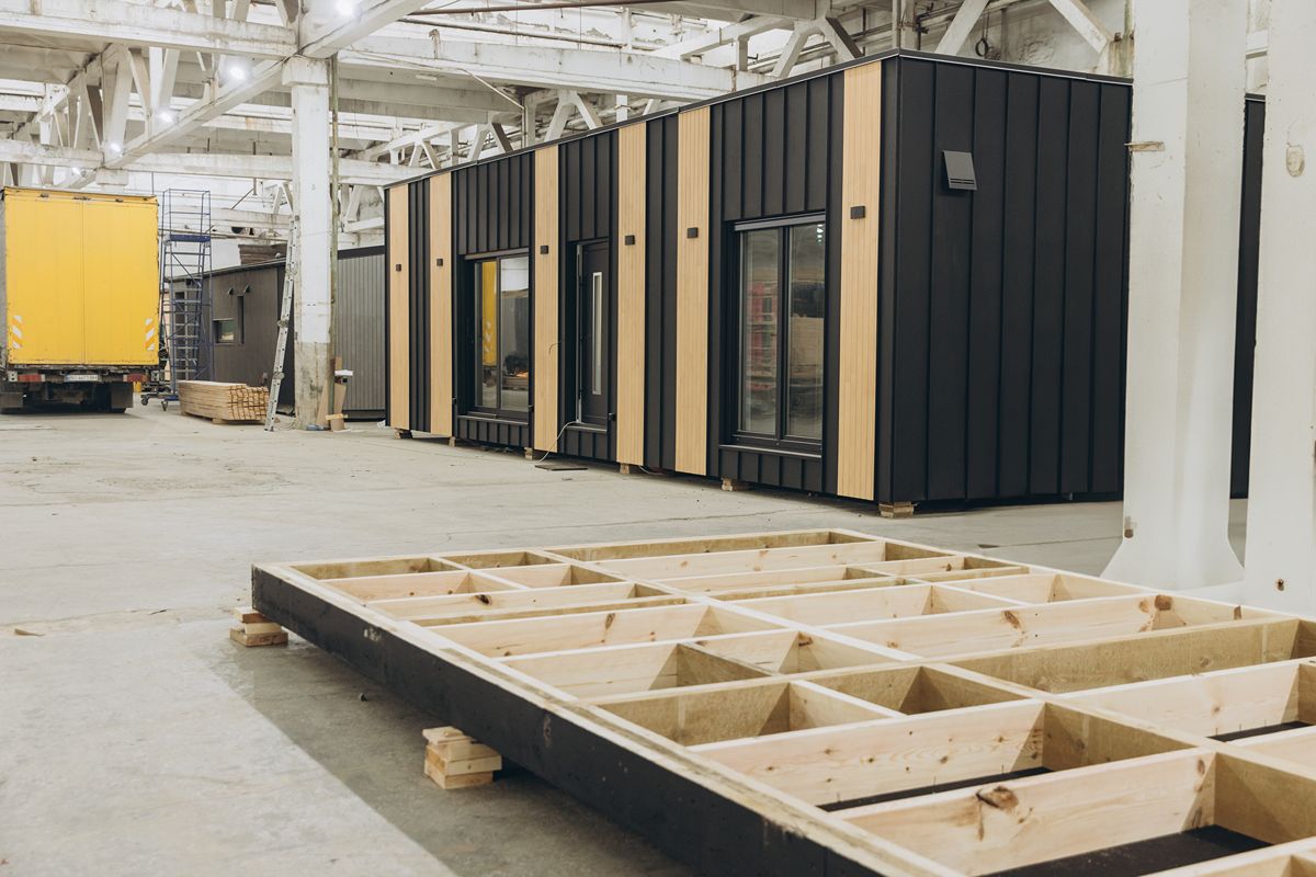 Modular container office units with insulated exterior panels positioned inside an industrial facility