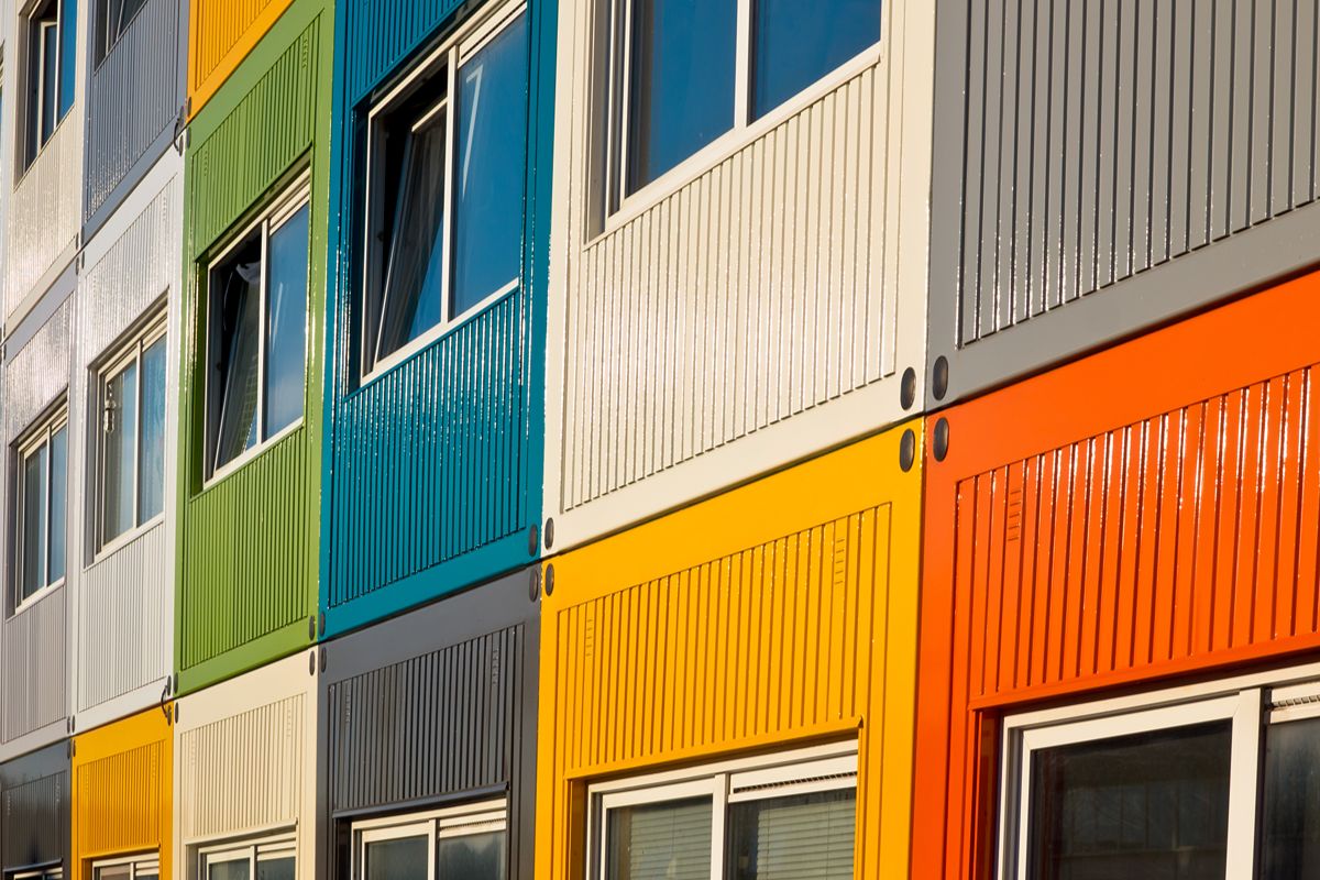 Modular prefab office units with colorful exterior panels and multiple windows arranged in a multi-level configuration
