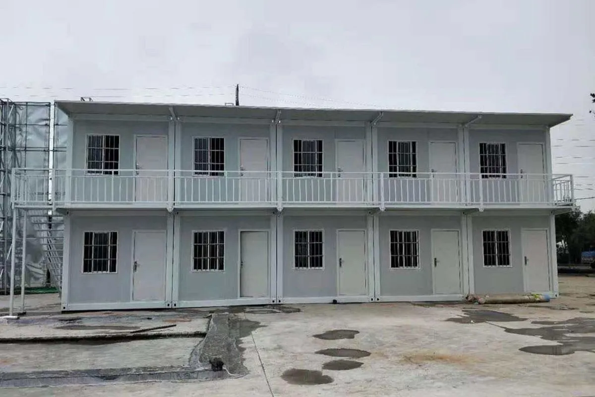 Two-story prefab residential building with multiple doors, windows, and an exterior walkway for faster housing development