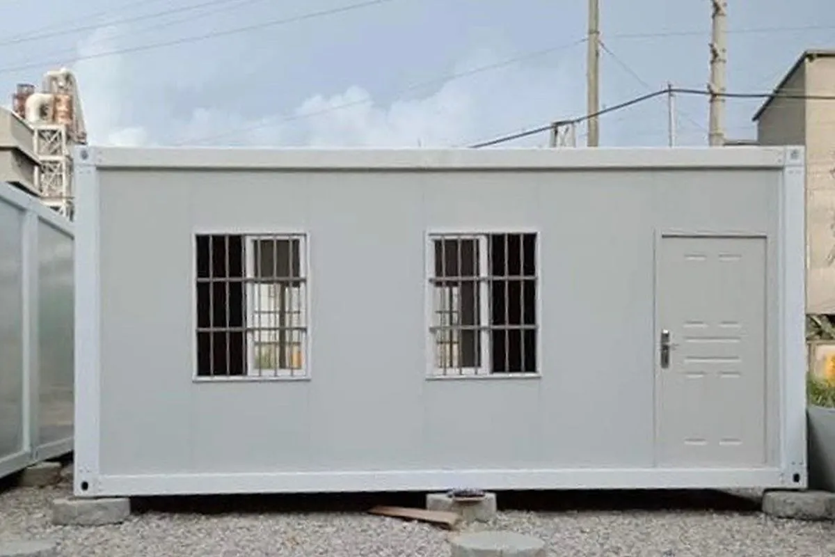 Compact single-story prefab rental unit with two windows and a front door installed on a prepared site