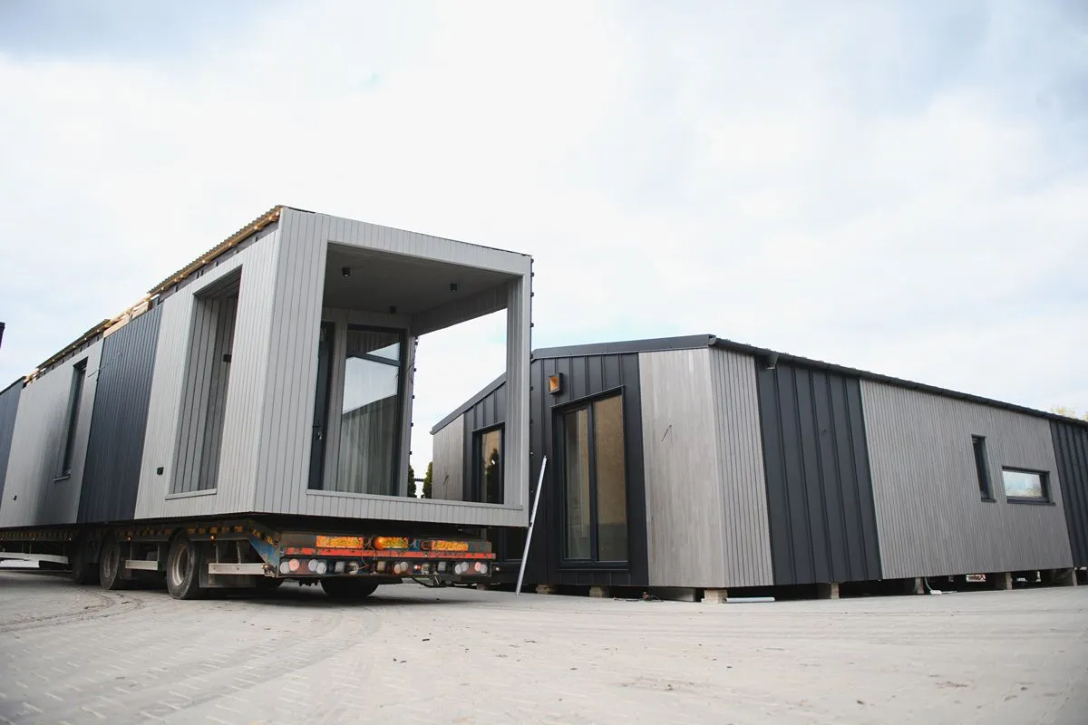 Modular prefab house units positioned for transport and installation while maintaining site access and required clearances