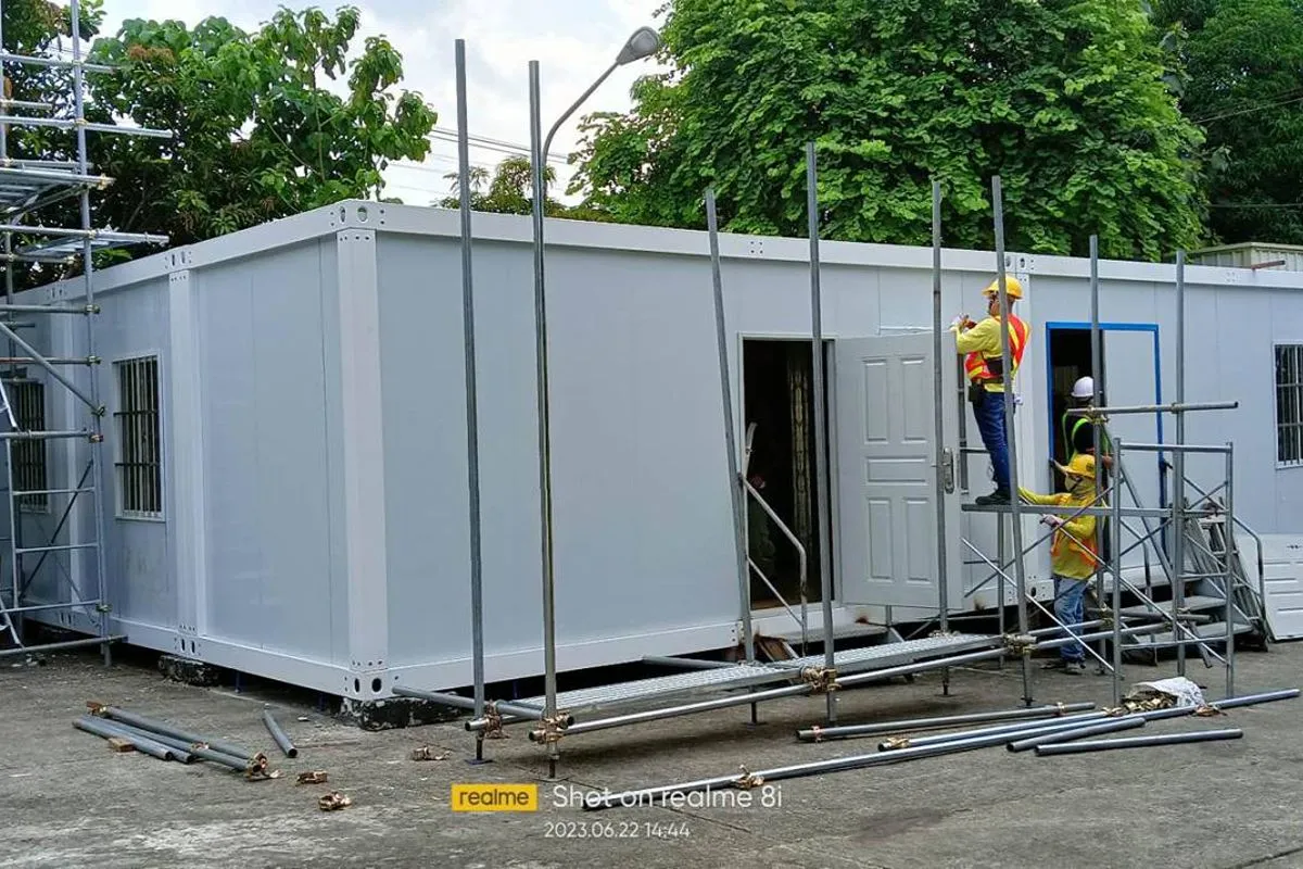 Prefab rental units under construction with workers, scaffolding, and standardized modular layouts
